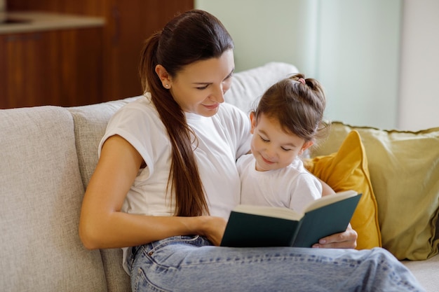 Baby development mother reading book with her cute toddler daughter at home