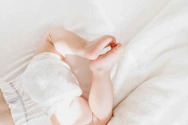 Baby in a diaper lies on a white bed top view copy space