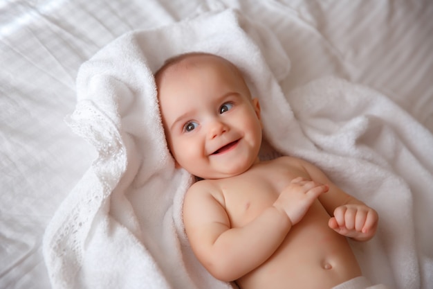 自宅のベッドで横になっているおむつの赤ちゃんの笑顔