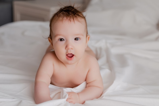 baby in a diaper lying on the bed at home