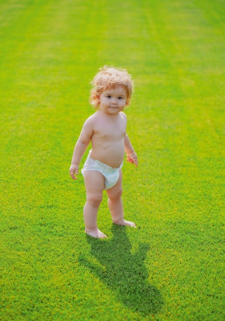 Baby die blootsvoets op groen gras loopt in zonnige zomeravond