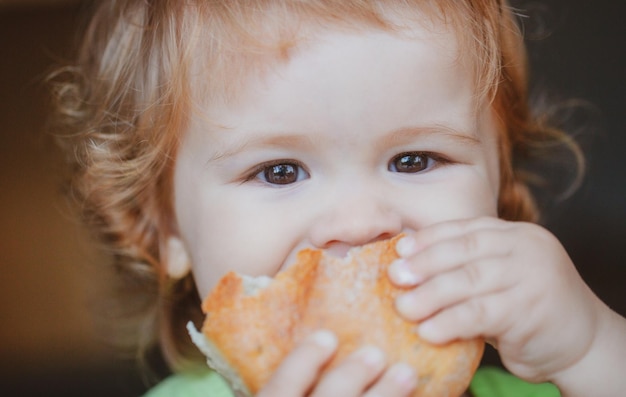 Baby die broodje brood eet close-up gezicht schattig peuter kind dat sandwich eet zelfvoedend concept