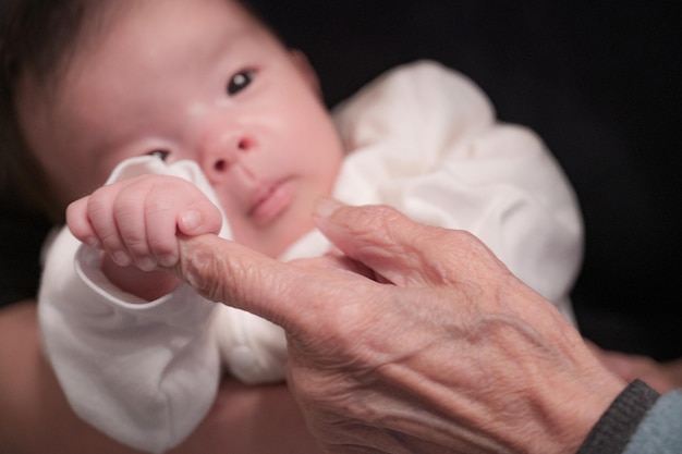 Baby die de hand van een oudere vrouw vasthoudt