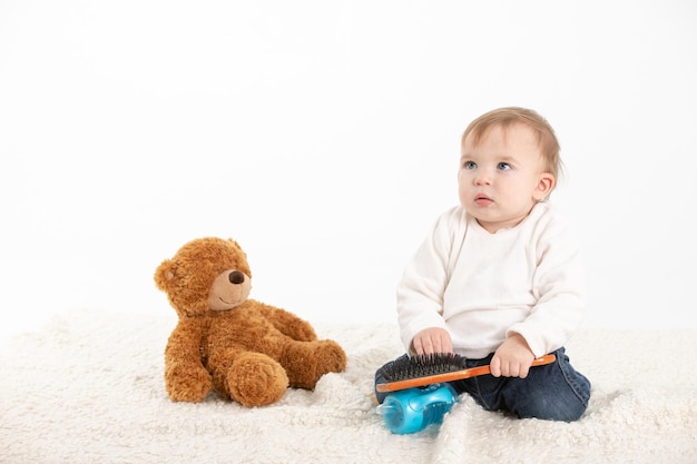 Baby die zijn haar kamt met een teddybeer aan zijn zijde