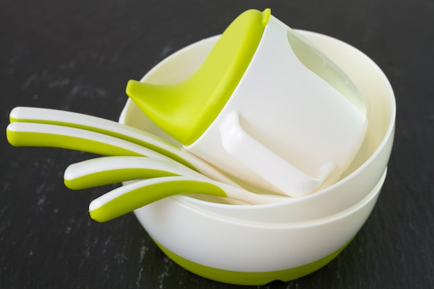 Baby dishes and spoons on black surface