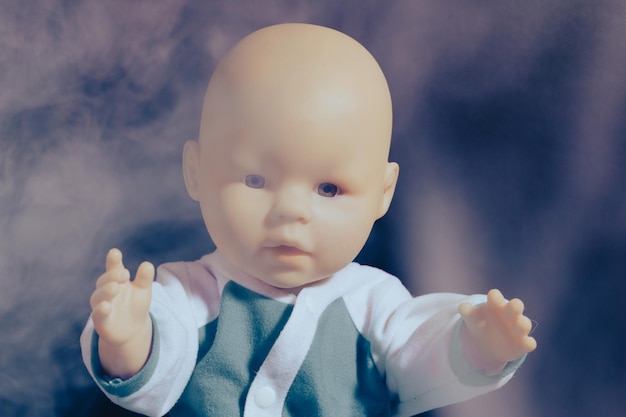 Baby doll in smoke on a dark background the concept of smoking in the presence of children