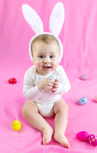 Baby dressed like a bunny with Easter eggs for Easter holiday