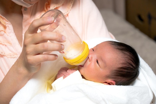 Ребенок пьет молоко в детской бутылочке
