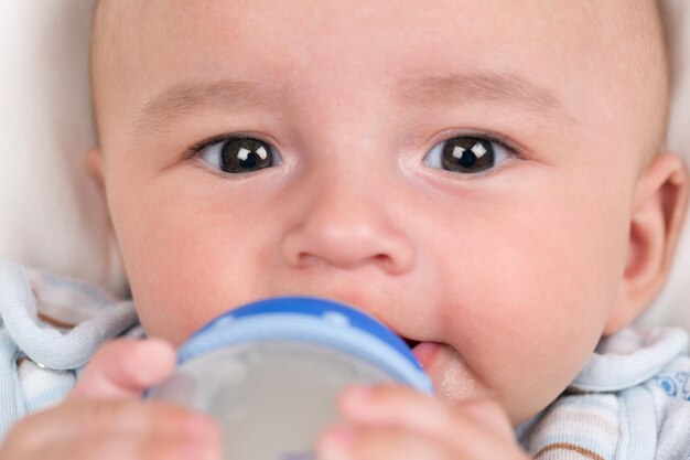 Baby drinking milk and holding the bottle