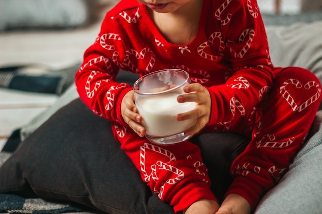 A baby drinks milk in a glass at Christmas