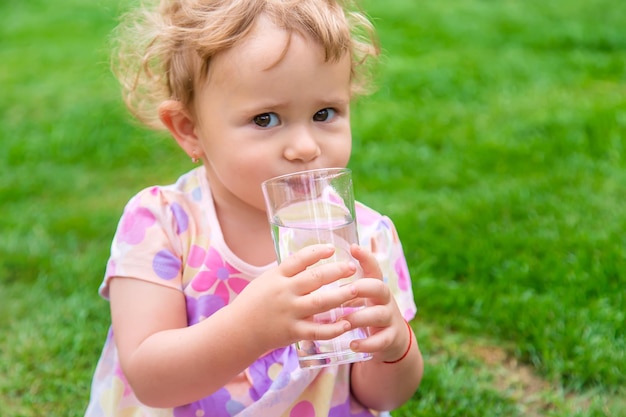 Ребенок пьет воду из стакана Выборочный фокус