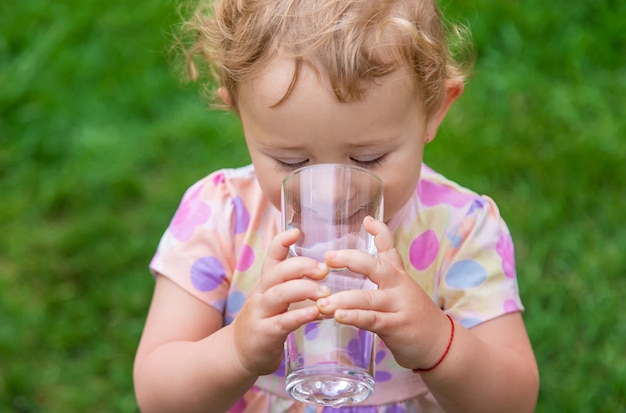 Baby drinks water from a glass Selective focus