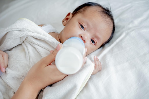 Baby drinkt melk uit fles gevoed door moeder