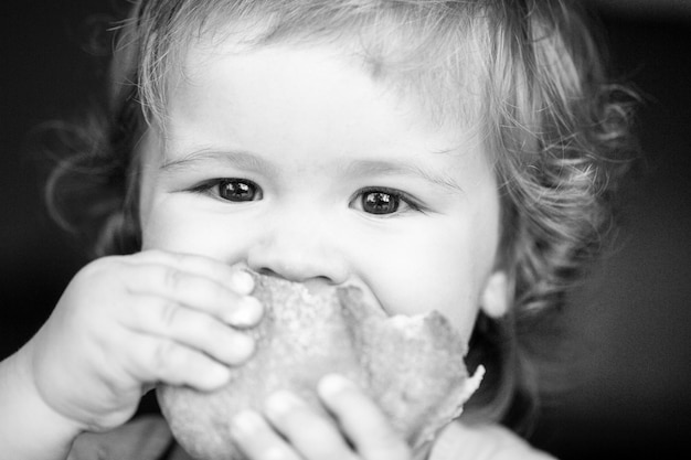 Baby eating bun bread close up face cute toddler child eating sandwich self feeding concept