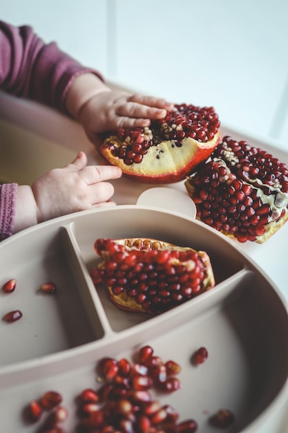 Baby eats pomegranate first complementary feeding concept