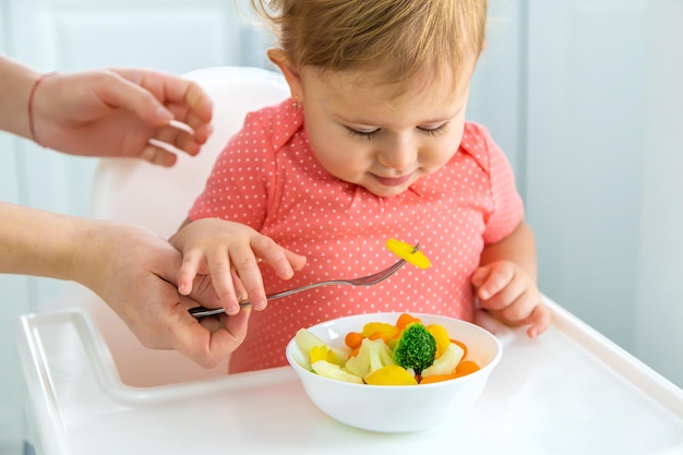 아기는 의자에 야채를 먹는다 선택적 초점 아이