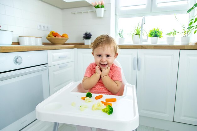 The baby eats vegetables on a chair Selective focus