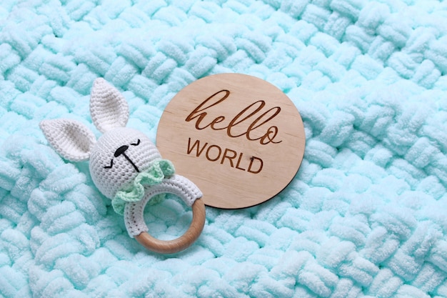Photo baby eco wooden toy beanbag  wooden tablet hello world on mint soft plaid backgroundtop view