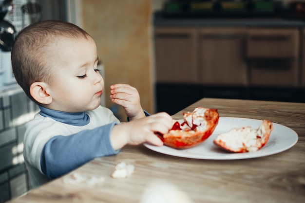 Baby eet een granaatappel, rijp en sappig, erg lekker en vrolijk