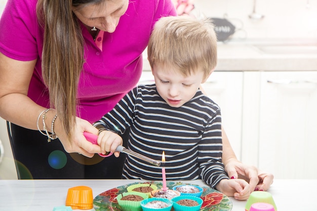 Baby en mama steken de verjaardagskaars aan op muffins