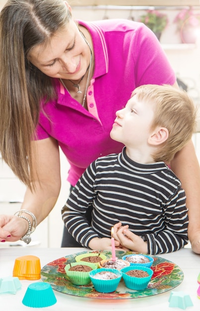 Baby en mama steken de verjaardagskaars aan op muffins