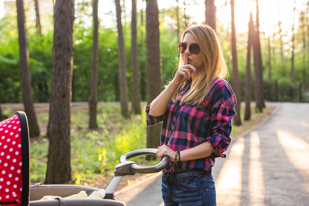 Baby en moederschap concept vrouw met kinderwagen die het stiltegebaar doet