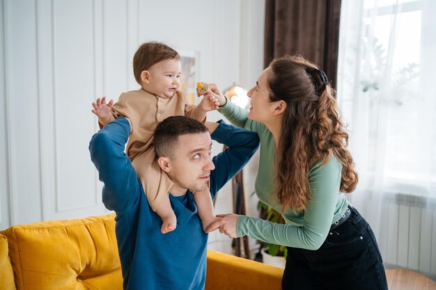 Baby on fathers shoulders mom playing with little son gives the boy a pacifier