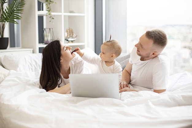 Baby feeding mom with fruit roll while dad using laptop