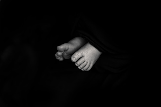 Baby feet on black background newborn photography idea. Negative space photo