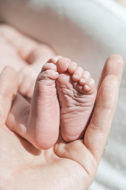 Baby feet The father holds with tenderness and love in his hands the small legs of newborn New life