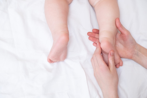 Photo baby feet in mom's hands. the feet of a tiny newborn baby on a female hand shape close up. mom and her child.