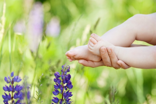 Baby feet in mother hands. Tiny Newborn Baby's feet on female Shaped hands closeup. Mom and her Child. Happy Family concept. Beautiful conceptual image of Maternity