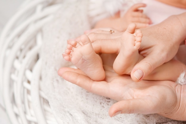 어머니 손에 아기 발. 여성 모양의 손 근접 촬영에 작은 신생아의 발. 엄마와 그녀의 아이. 행복한 가족 개념입니다. 출산의 아름다운 개념적 이미지