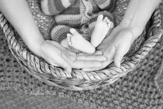 Baby feet in mother hands Tiny Newborn Baby's feet on female Shaped hands closeup Mom and her Child