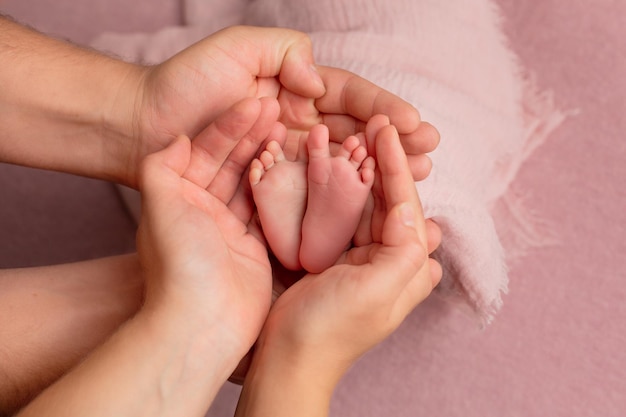 Baby feet in mother's hands. Legs of a tiny newborn in the arms close-up. Family and child. Happy fa