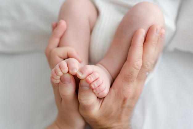 Baby feet in parent's hands. Small newborn fingers. White background natural and simple lifestyle