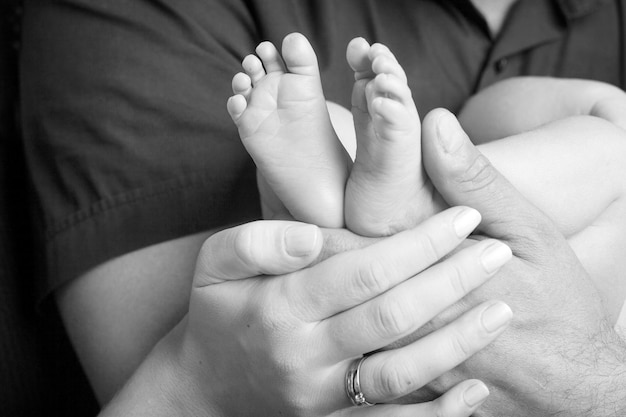 Baby feet in parents hands Tiny Newborn Baby's feet on parents shaped hands closeup Parents and they