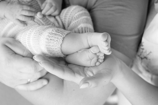両親の手の中の赤ちゃんの足 両親の形をした手のクローズアップに小さな新生児の赤ちゃんの足