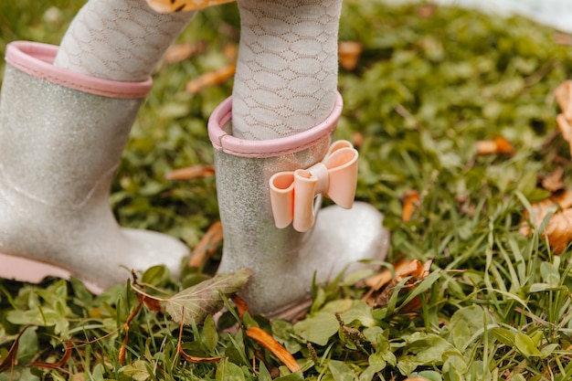 I piedi del bambino con gli stivali di gomma si chiudono. il bambino corre attraverso le pozzanghere in una giornata autunnale.