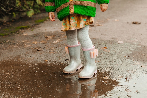 Foto i piedi del bambino con gli stivali di gomma si chiudono. il bambino corre attraverso le pozzanghere in una giornata autunnale.