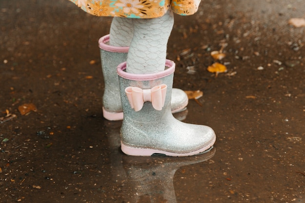 Baby feet in rubber boots close up. the child runs through the
puddles on an autumn day.