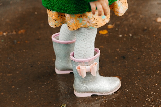 Baby feet in rubber boots close up. the child runs through the
puddles on an autumn day.