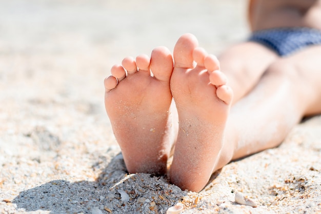 Foto piedi del bambino nella sabbia in estate