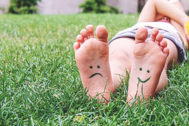 Baby feet with paint pattern are smiling and sad on the green grass. Selective focus. nature.