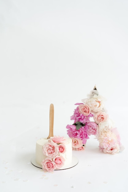 Photo baby first year photoshoot idea. cake smash decorations with flowers and white cake.