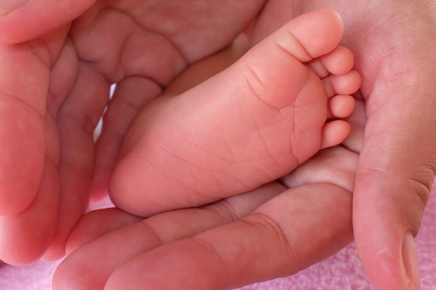 赤ちゃんの母親の手で足。