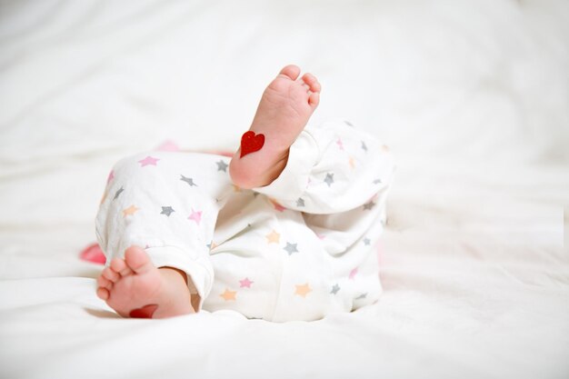 Baby foots with hearts on their feet A newborn baby is lying on the bed