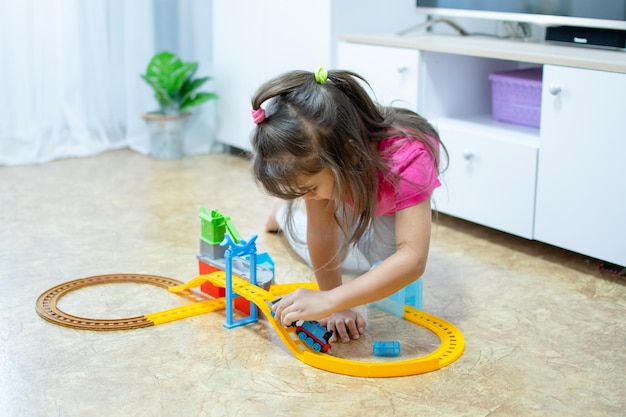 아기 게임. 작은 영리한 백인 아이가 다채로운 장난감 철도를 연주하고 초기 발달을 위해 기차를 타고 있습니다.