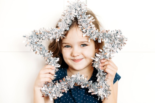 Baby girl in blue dress holding new year's Christmas decoration star