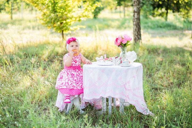 Baby girl celebrates her first birthday with cake and balloons in nature